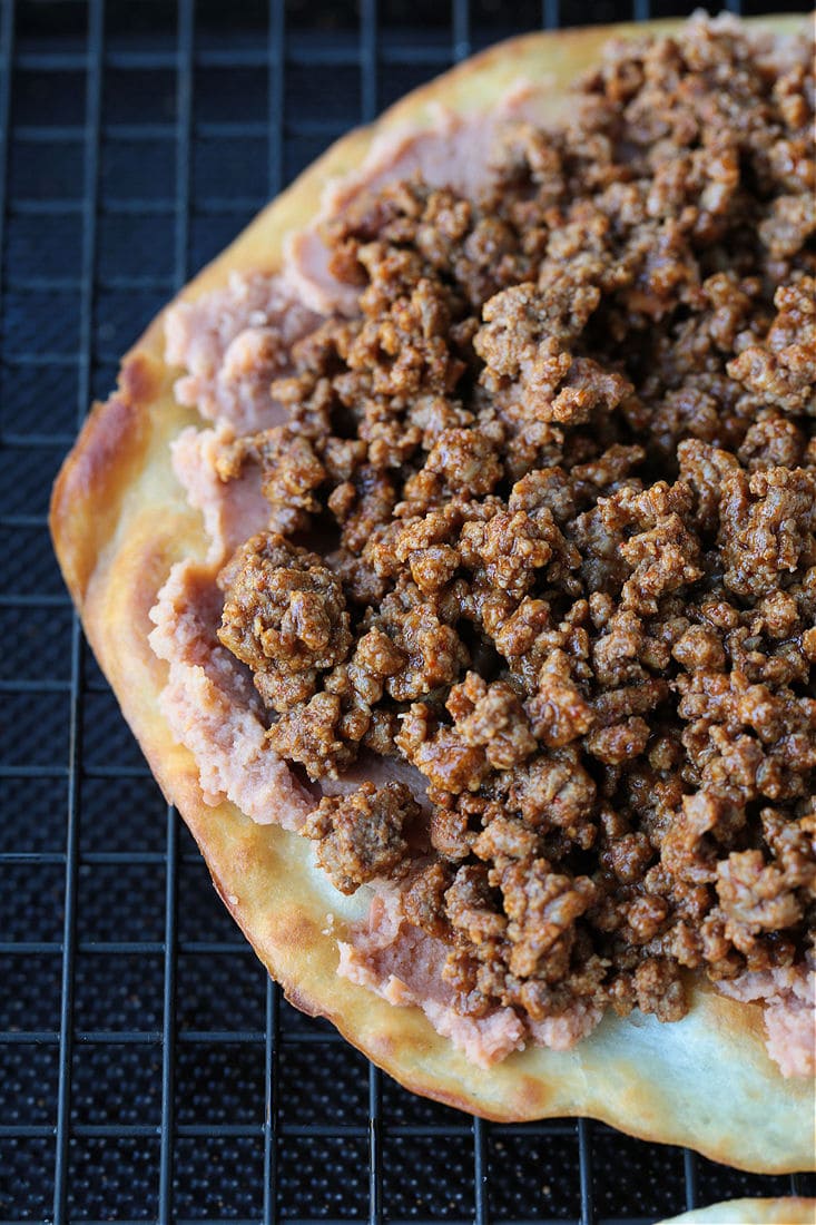 taco meat and refried beans on a fried tortilla