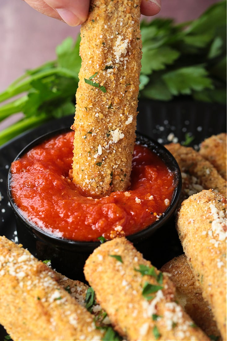 mozzarella stick being dipped into sauce