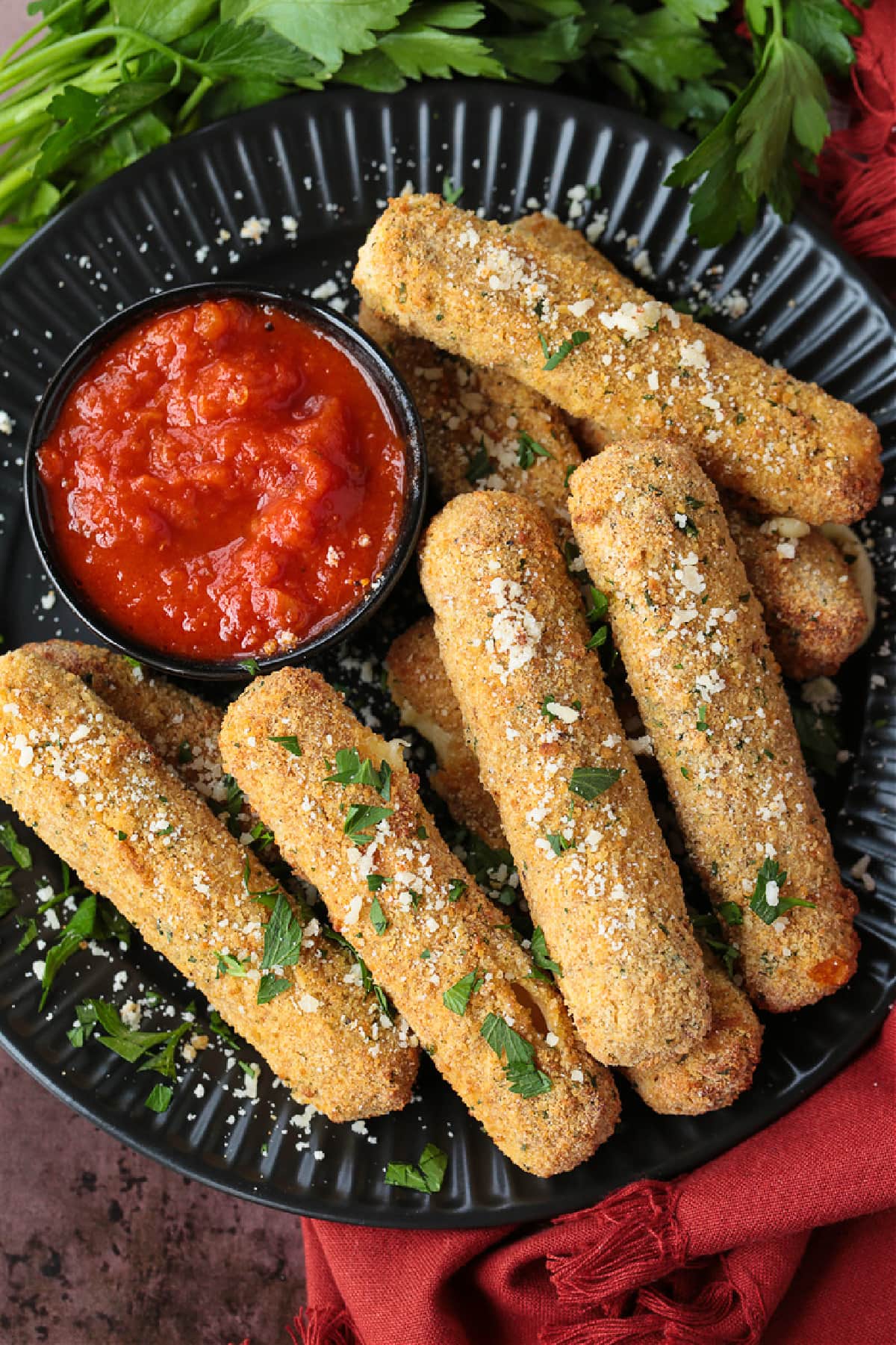 Air Fryer Mozzarella Sticks turn out fabulously crispy without any oil! Brown and crispy on the outside and cheese-pull worthy on the inside! mozzarella sticks on a black plate with sauce