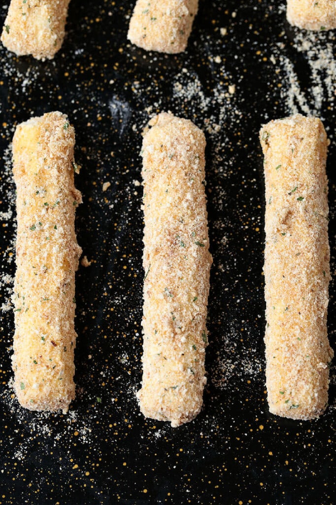 Air Fryer Mozzarella Sticks turn out fabulously crispy without any oil! Brown and crispy on the outside and cheese-pull worthy on the inside! breaded mozzarella sticks on a baking sheet
