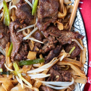 Close up of a serving dish of beef chow fun, with chopsticks