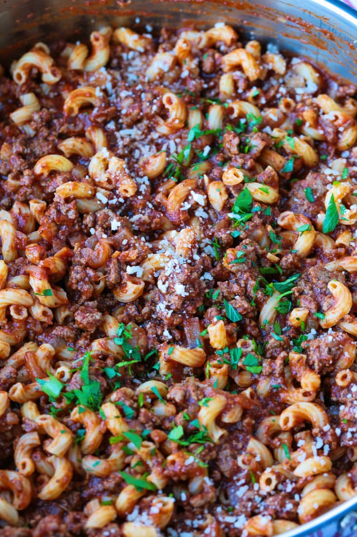 Close up of beefaroni in a serving dish, topped with parmesan and parsley