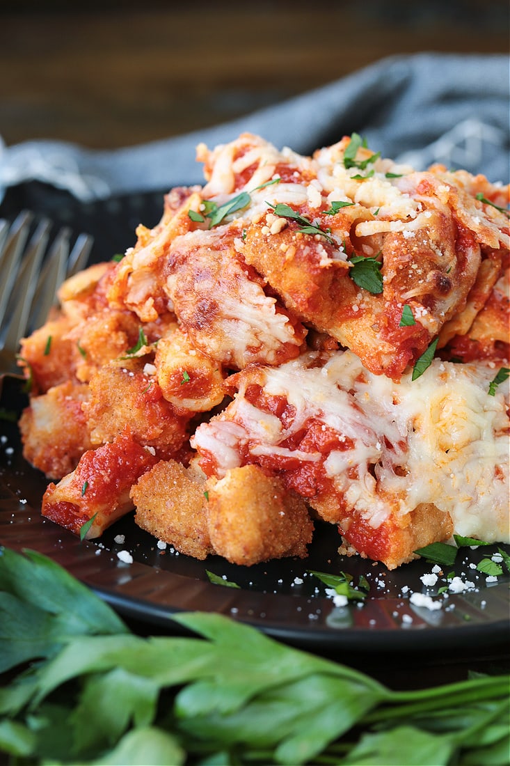 Chicken and pasta casserole on a black plate with fork