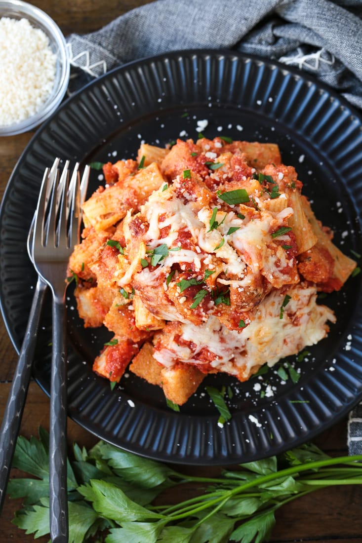 chicken and pasta casserole on a black plate with fork and cheese