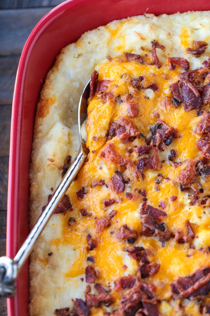 Spoon in mashed potato casserole topped with cheese and bacon