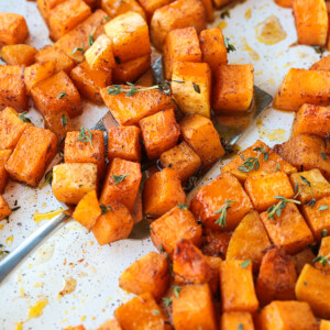 cubes ob butternut squash on a baking sheet with spatula