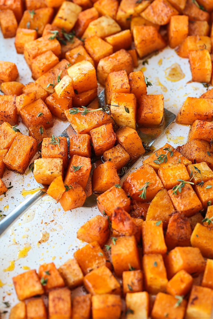 cubes of butternut squash on a baking sheet with spatula