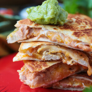 A stack of chicken quesadilla triangles, with a dollop of guacamole on top