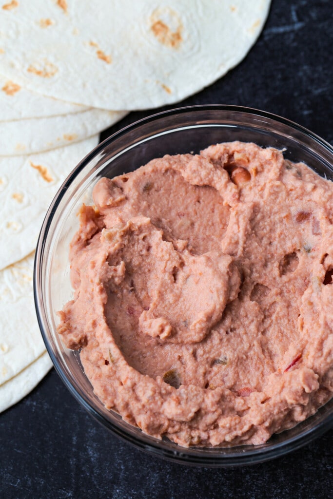 refried beans with tortillas on a board