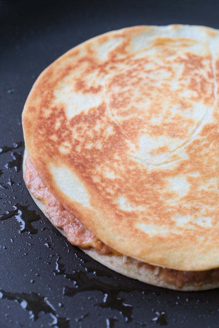 A chicken quesadilla cooking in a pan