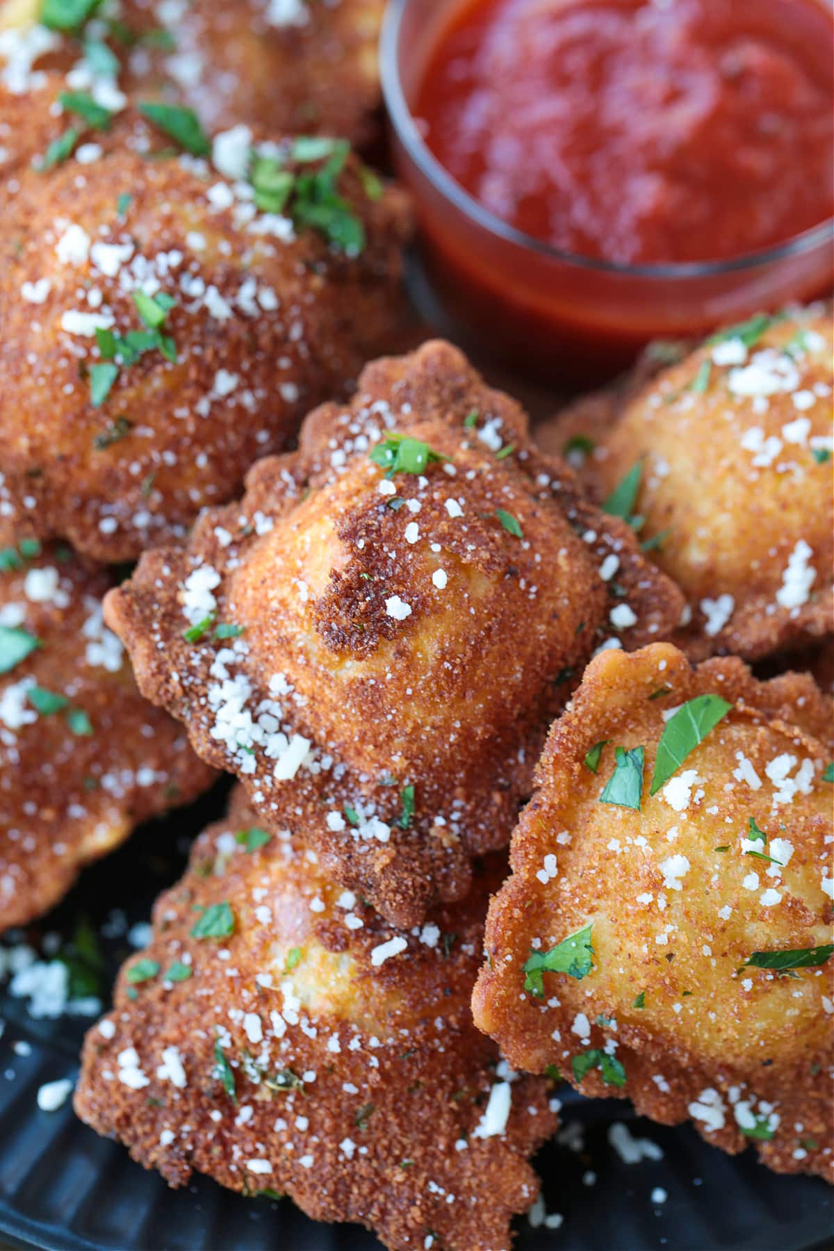 This fried ravioli recipe is crispy on the outside and soft and cheesy on the inside! Dip in marinara sauce for an addicting party appetizer! fried ravioli with marinara sauce on the side