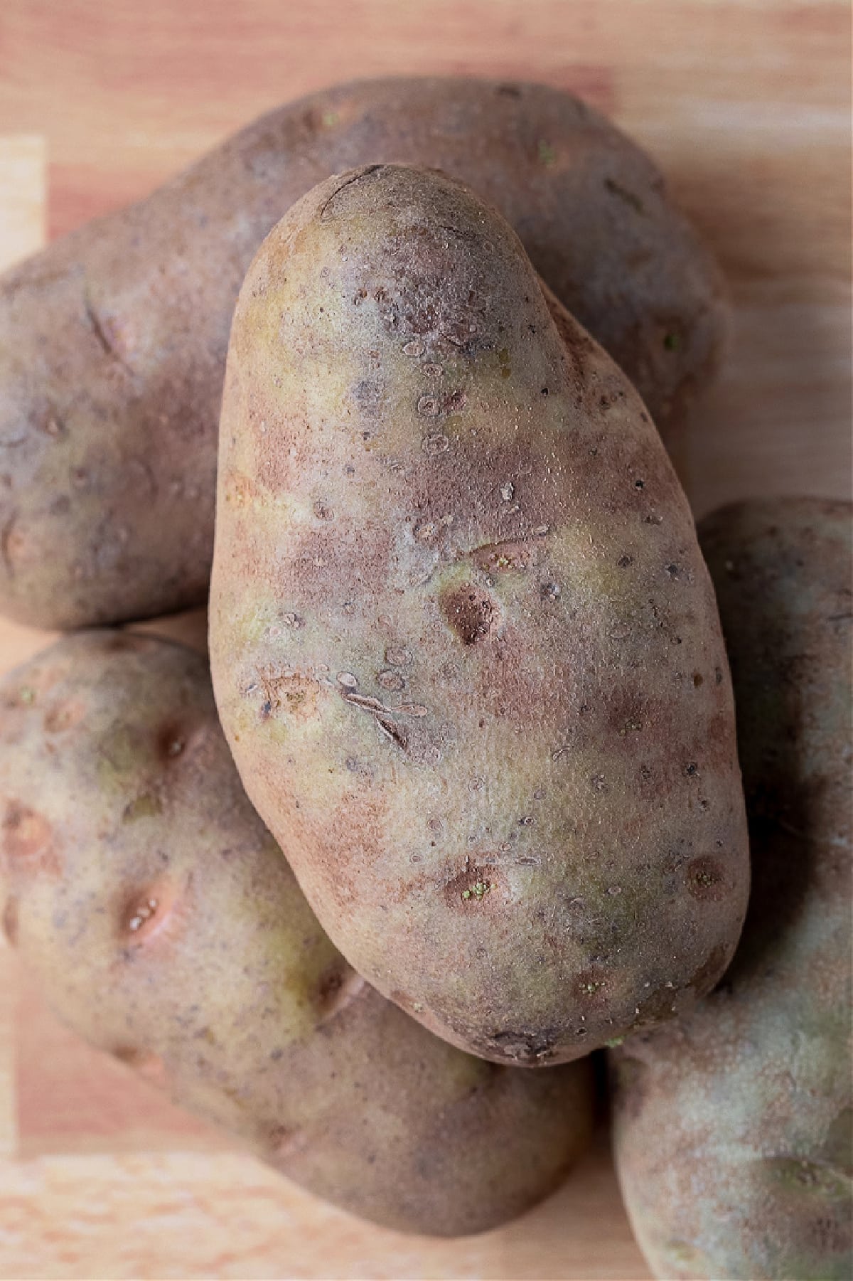 These fluffy Air Fryer Baked Potatoes have the most crispy skin! Free up the oven and let the air fryer do the work for you! potatoes stacked on a board
