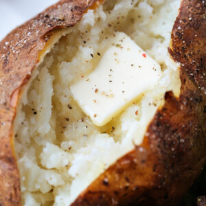 close up of cut ope baked potato with butter