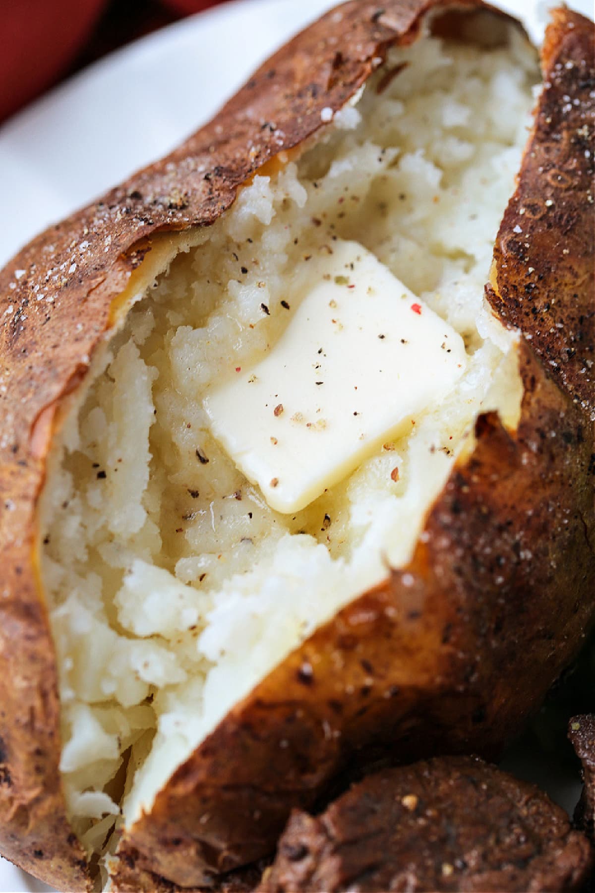 These fluffy Air Fryer Baked Potatoes have the most crispy skin! Free up the oven and let the air fryer do the work for you! close up of cut ope baked potato with butter