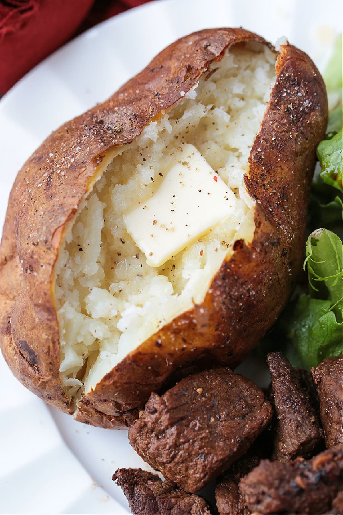 These fluffy Air Fryer Baked Potatoes have the most crispy skin! Free up the oven and let the air fryer do the work for you! baked potato on plate with butter