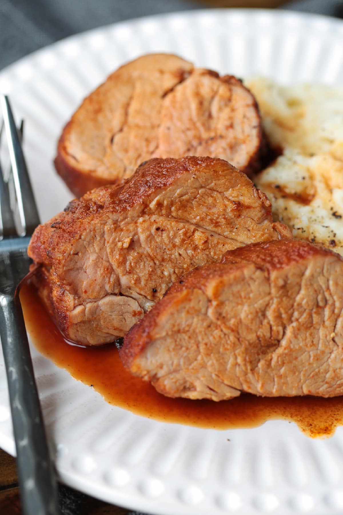Treat your taste buds to a juicy air fryer pork tenderloin! The air fryer helps lock in the juices and gives the pork a golden-brown finish. slices of pork tenderloin on plate with potatoes