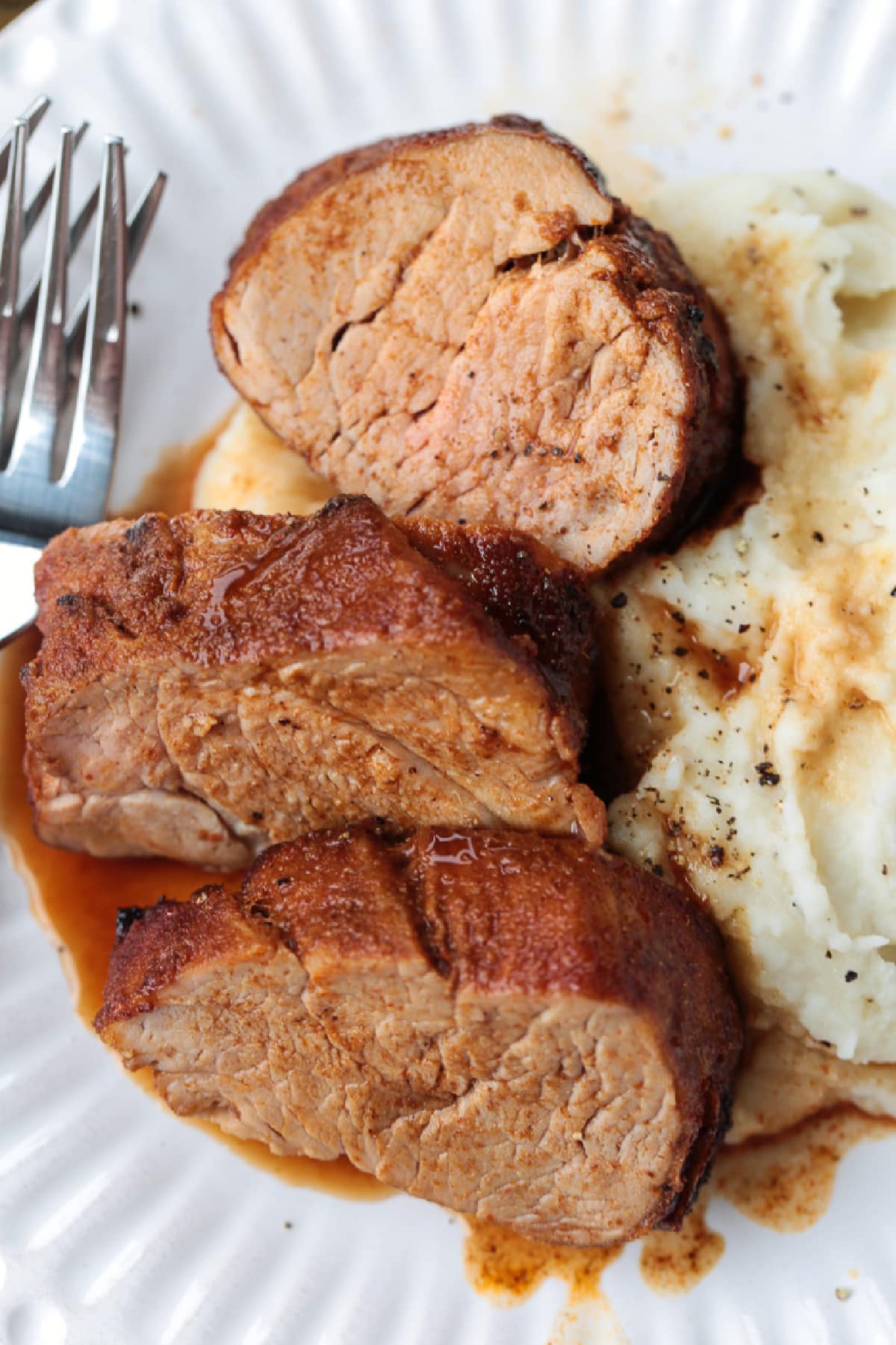 Treat your taste buds to a juicy air fryer pork tenderloin! The air fryer helps lock in the juices and gives the pork a golden-brown finish. slices of pork tenderloin on plate with potatoes