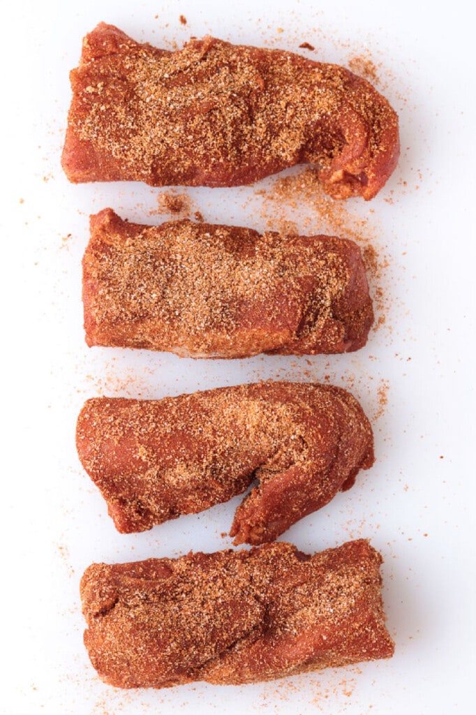 Treat your taste buds to a juicy air fryer pork tenderloin! The air fryer helps lock in the juices and gives the pork a golden-brown finish. sliced pork on a board with seasoning
