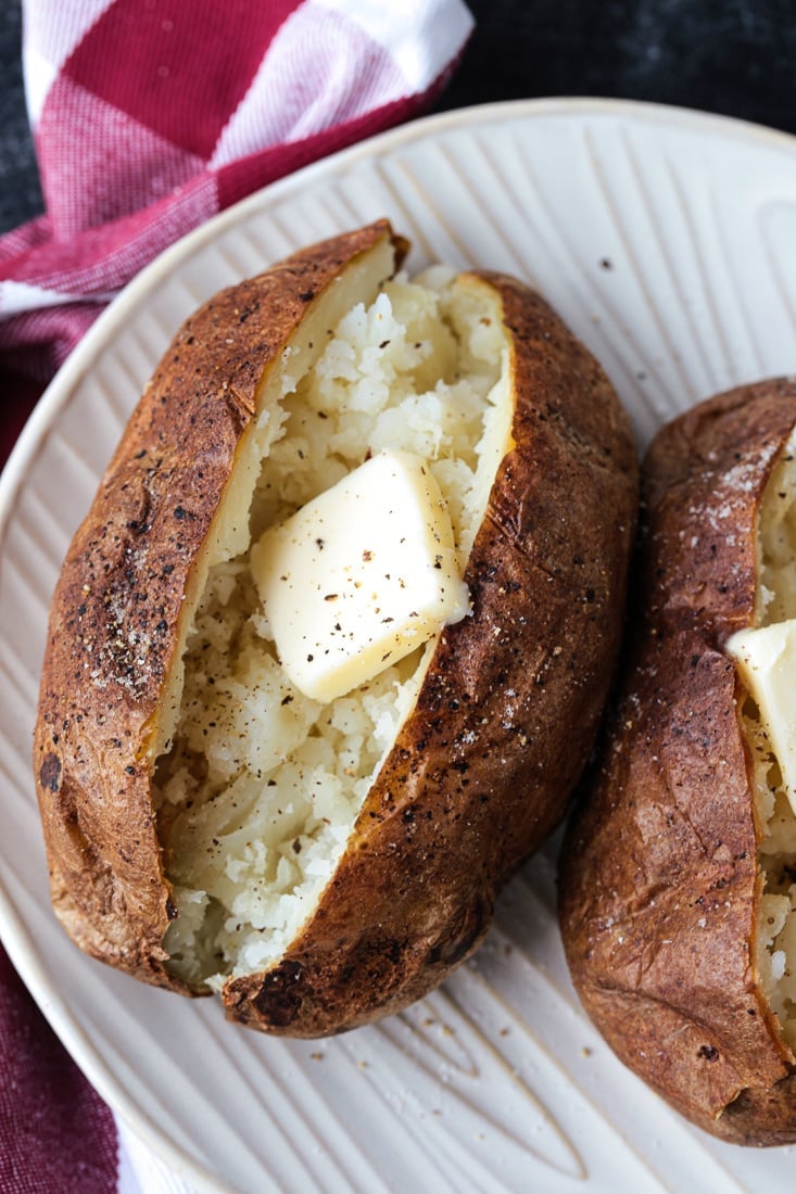 Breakfast Baked Potatoes are stuffed with fluffy scrambled eggs, cheese and crispy bacon! So fun for brunch, breakfast and even dinner! baked potato cut open with butter