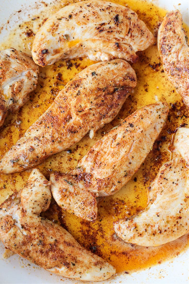 seasoned chicken tenderloins browning in a skillet