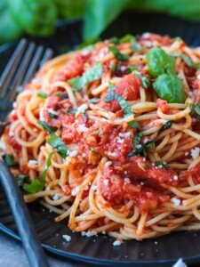 spaghetti on a black dish with forks on the side