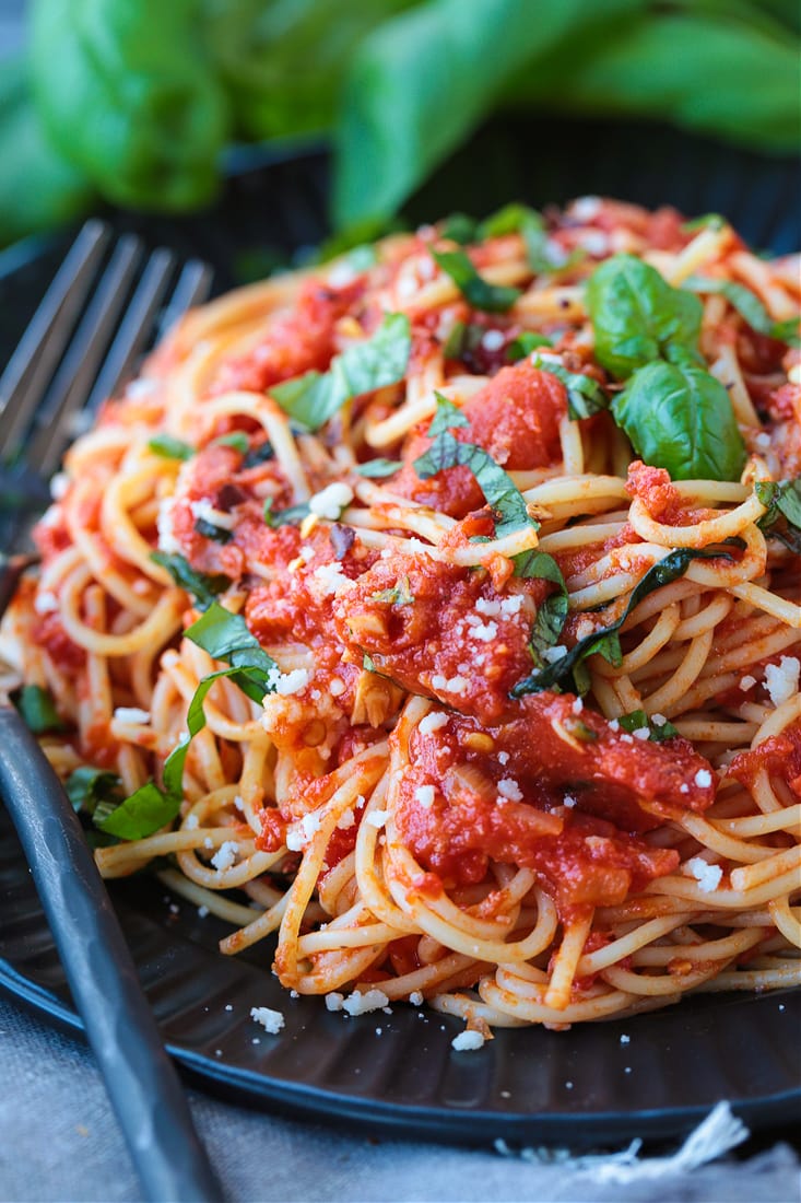 spaghetti on a black dish with forks on the side