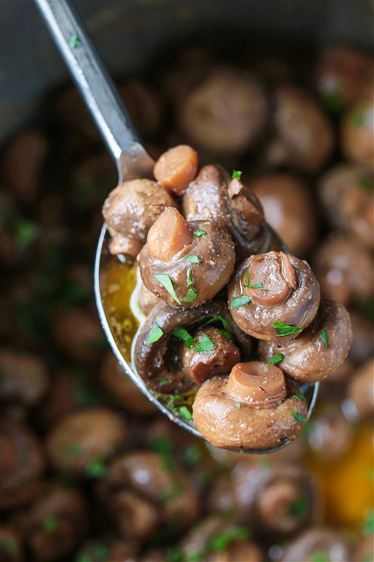 mushrooms cooked in butter and wine on a serving spoon