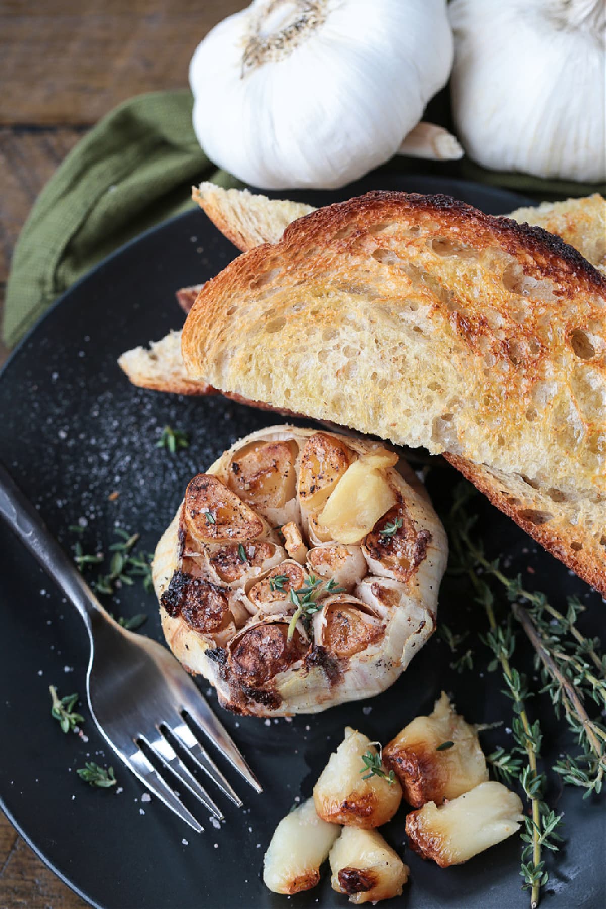 Air Fryer Roasted Garlic is done in half the time! Creamy, nutty roasted garlic that can be used as a spread or in many different recipes! roasted garlic on a plate with toast and fork