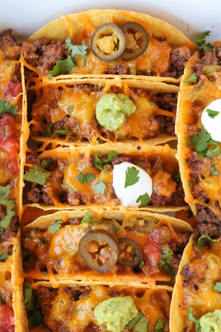 baked tacos in baking dish with guacamole and sour cream