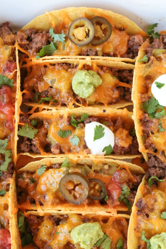 Kick up taco night with these addicting, crispy Baked Tacos! Super easy to make for parties or every day dinners, and everyone loves them! baked tacos with toppings in baking dish
