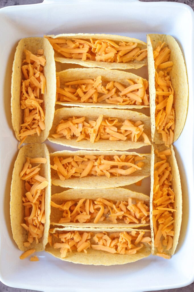 Kick up taco night with these addicting, crispy Baked Tacos! Super easy to make for parties or every day dinners, and everyone loves them! taco shells in baking dish with cheese