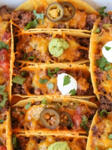 baked tacos in baking dish with guacamole and sour cream