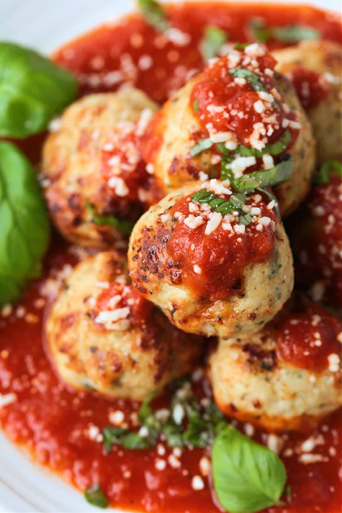 Our Air Fryer Turkey Meatballs are super flavorful and juicy! An easy to make dinner recipe that's ready to serve in just 15 minutes! turkey meatballs on a plate with sauce and basil