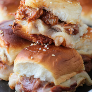 pulled pork sliders with cheese stacked on a plate