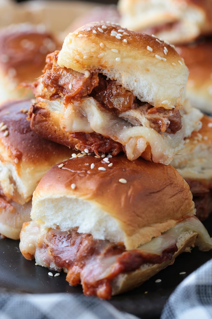 pulled pork sliders with cheese stacked on a plate