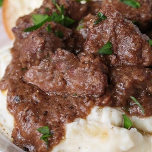 slow cooker beef tips with gravy on a bed of mashed potatoes