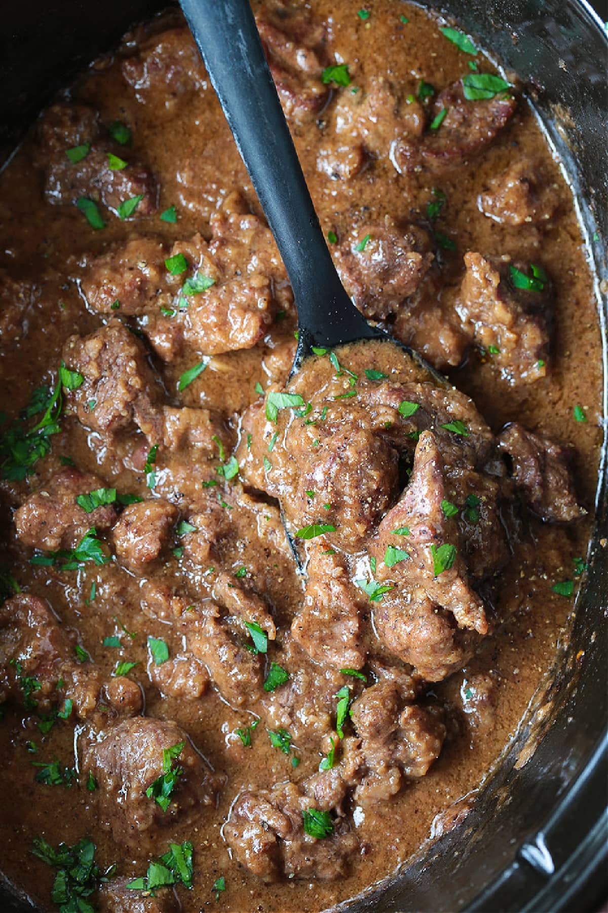 beef tips and gravy in slow cooker with spoon