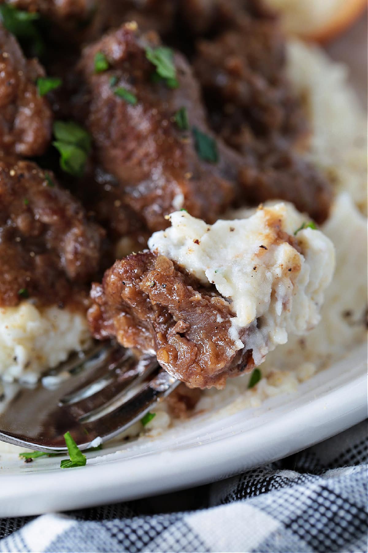 fork with bite of beef tips and gravy with mashed potatoes