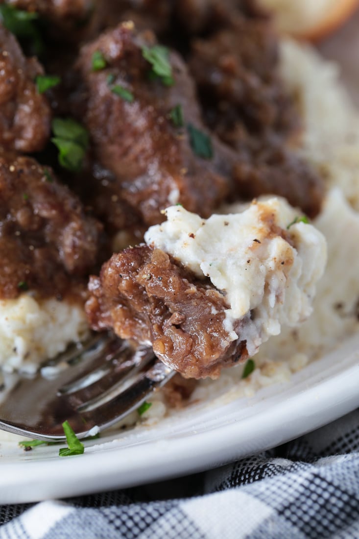 beef tips in gravy on a fork with mashed potatoes
