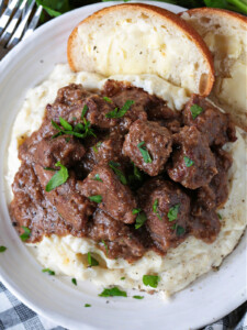 beef tips and gravy on mashed potatoes with bread and butter