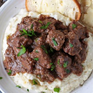 beef tips and gravy on mashed potatoes with bread and butter