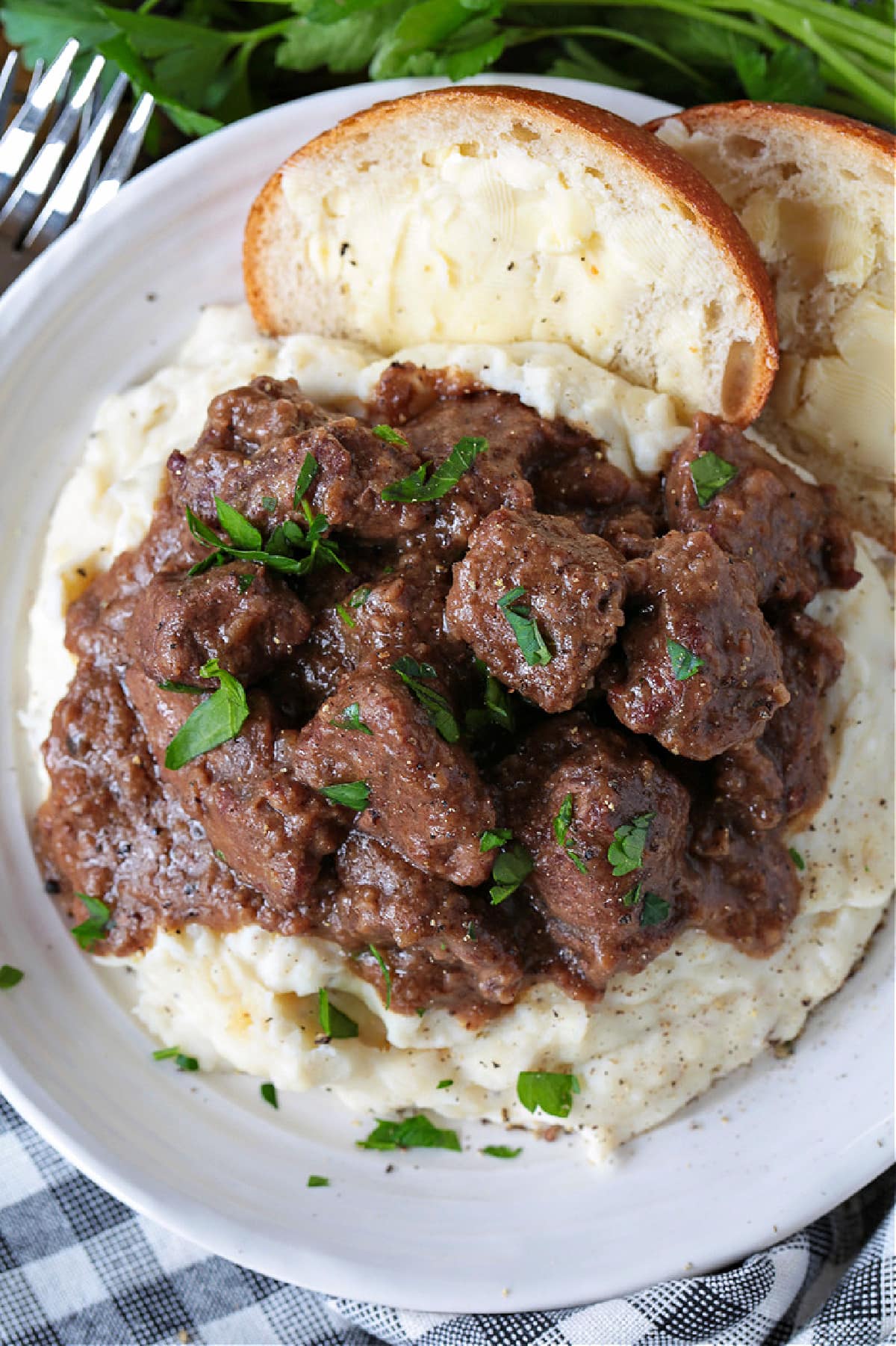 beef tips and gravy on mashed potatoes with bread and butter