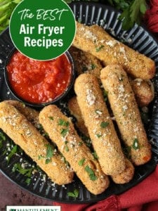 air fryer mozzarella sticks on black plate with sauce