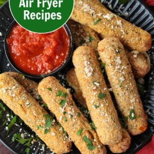 air fryer mozzarella sticks on black plate with sauce
