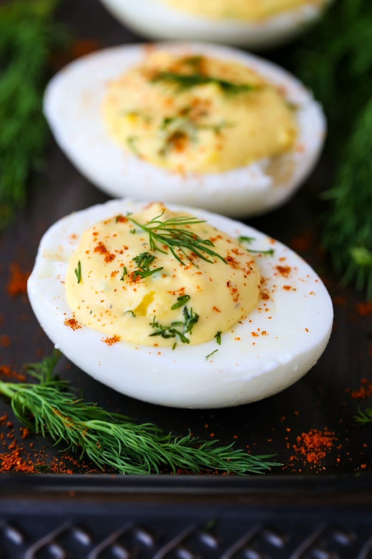 deviled eggs on a platter with fresh dill and paprika