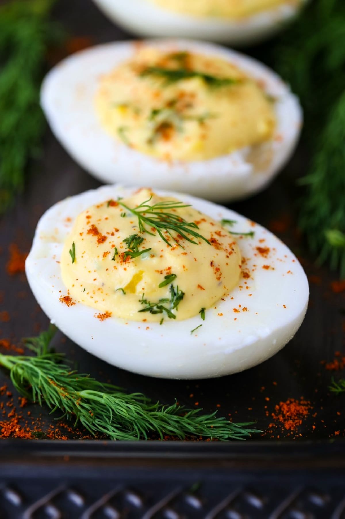 Classic Deviled Eggs are a favorite party or holiday appetizer! Hard boiled eggs with a creamy and tangy filling that everyone craves. deviled eggs on a platter with fresh dill and paprika