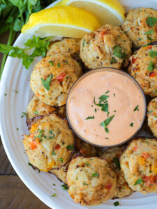 crab balls with dipping sauce on plate with lemons