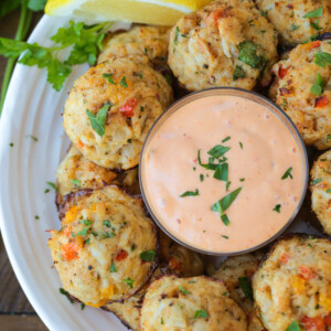 crab balls with dipping sauce on plate with lemons