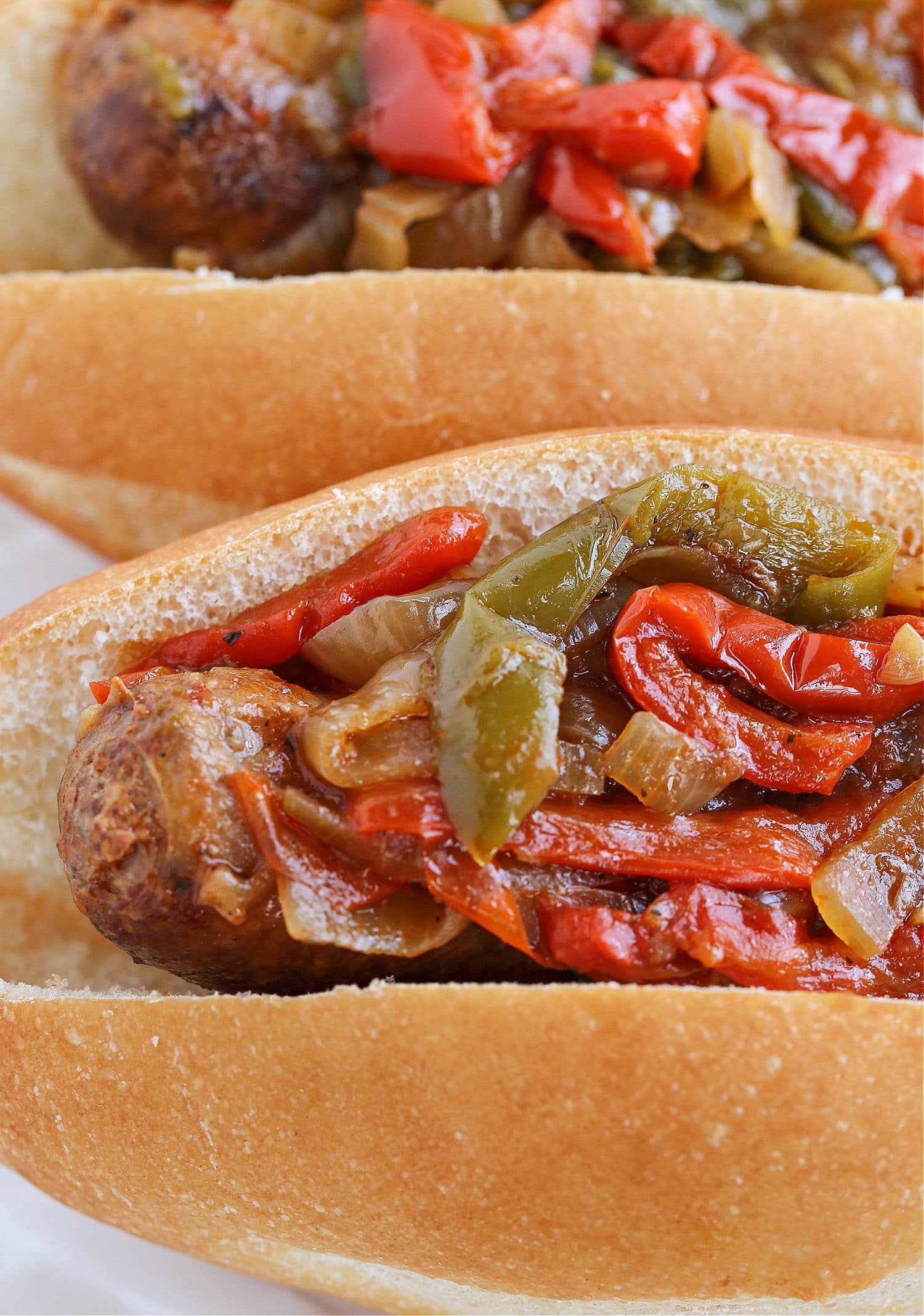 Our Crock Pot Sausage and Peppers are simmered in a marsala wine-tomato sauce that's so addicting! A fun dinner for parties and game days! sausage and peppers on a bun
