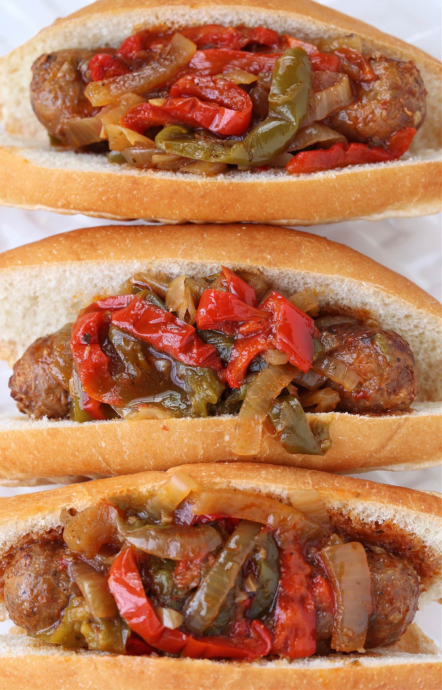 Our Crock Pot Sausage and Peppers are simmered in a marsala wine-tomato sauce that's so addicting! A fun dinner for parties and game days! sausage and pepper sandwiches on platter